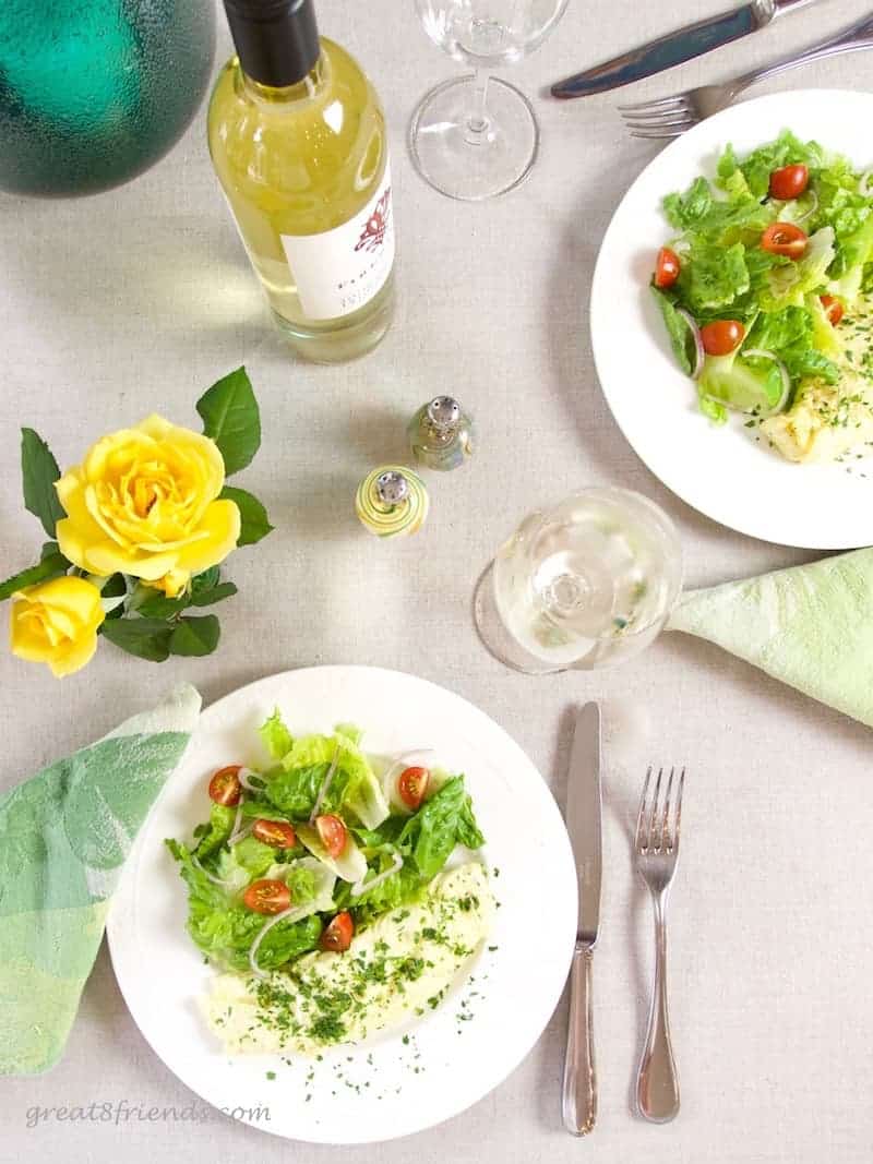 Overhead shot of table set with yellow roses, white wine and two plates of omelettes and salad.