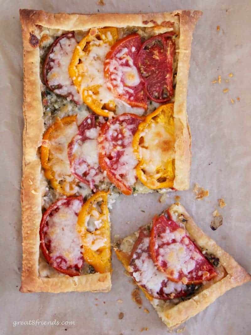 Baked onion and tomato tart with one piece cut out ready to serve.