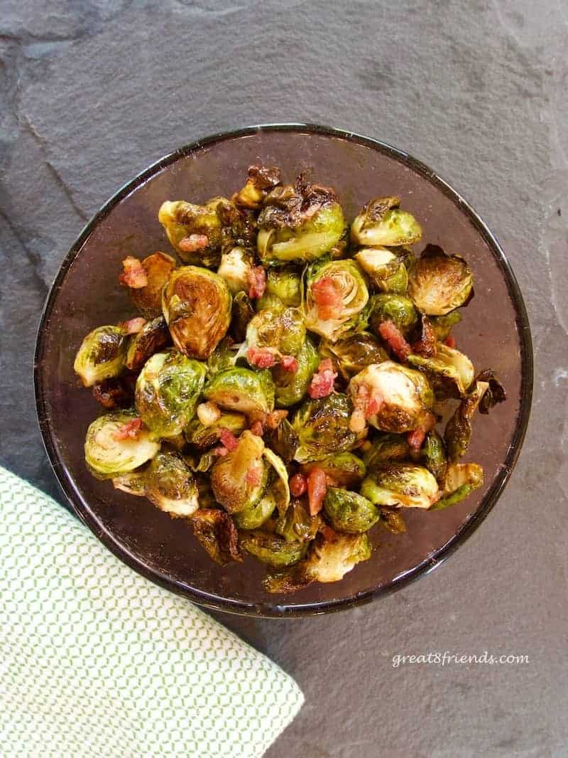 Roasted Brussels Sprouts with pancetta in a purple glass bowl.