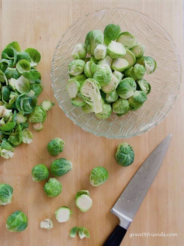 Overhead shot of Brussels Sprouts on a cutting board being cut in half.