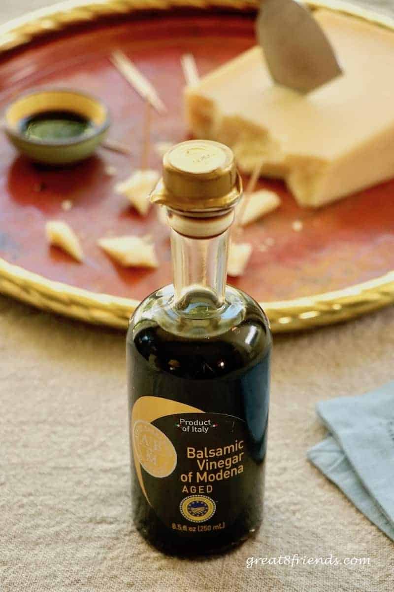 Bottle of balsamic vinegar with cheese in the background.