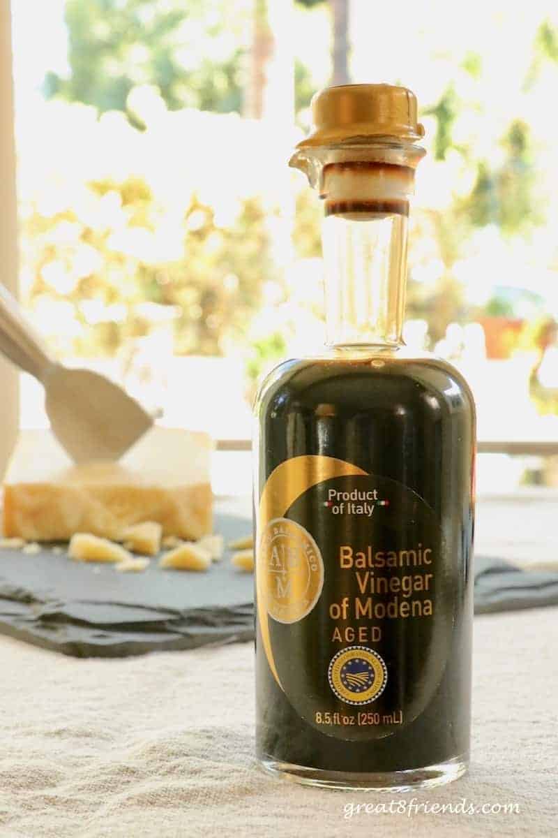 A bottle of Balsamic Vinegar of Modena with a hunk of Parmigiano Reggiano in the background.