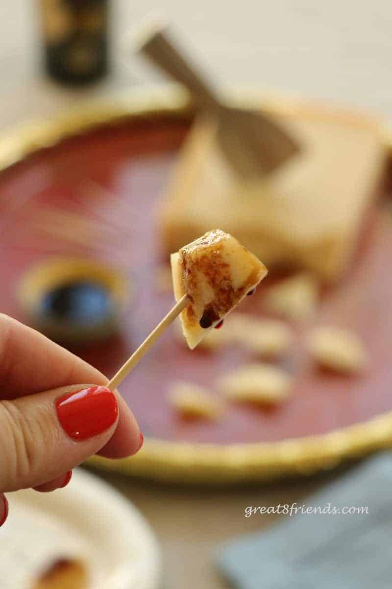 A small piece Parmigiano Reggiano on a toothpick drizzled with balsamic vinegar.