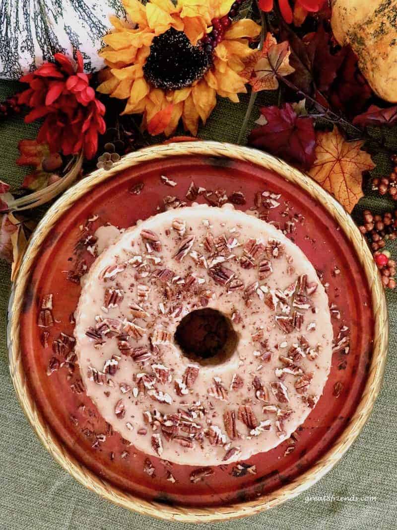 Overhead shot of glazed angel food cake sprinkled with pecans on a copper tray.