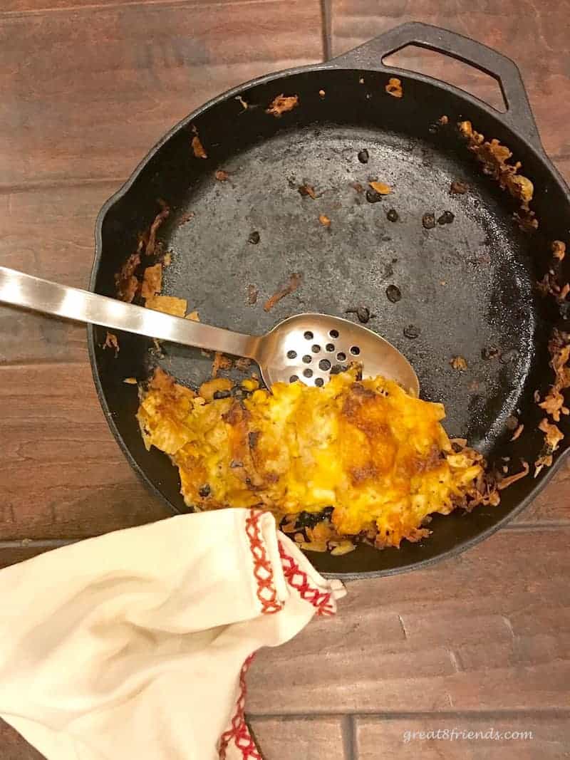 Cast iron skillet with only one serving of cheesy nachos left.