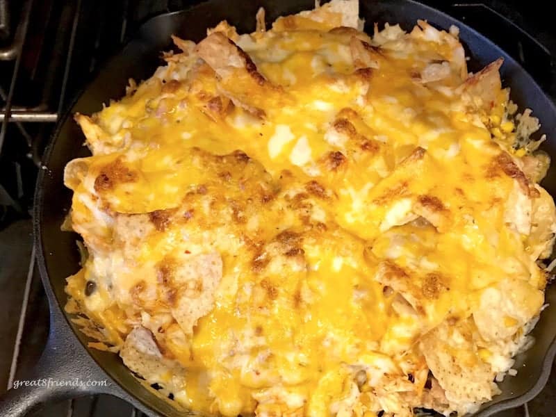 Overhead shot of cheesy nachos in cast iron skillet.