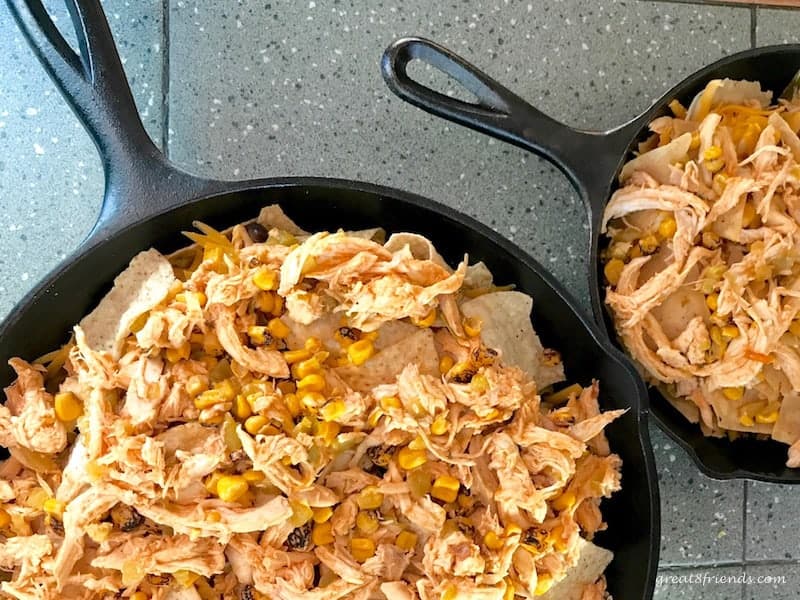 Overhead shot of two cast iron skillets with chicken nachos.
