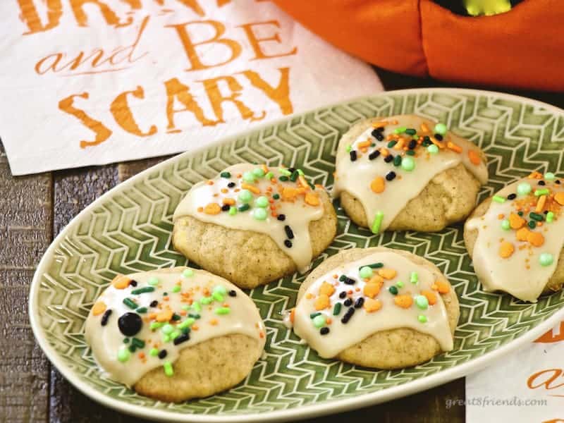Pumpkin cookies with sprinkles on top on a green plate.