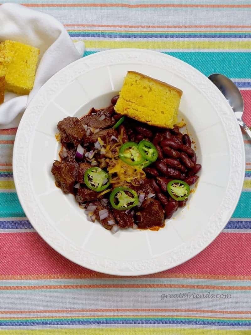 Overhead shot of white rimmed bowl filled with chili and a piece of cornbread.