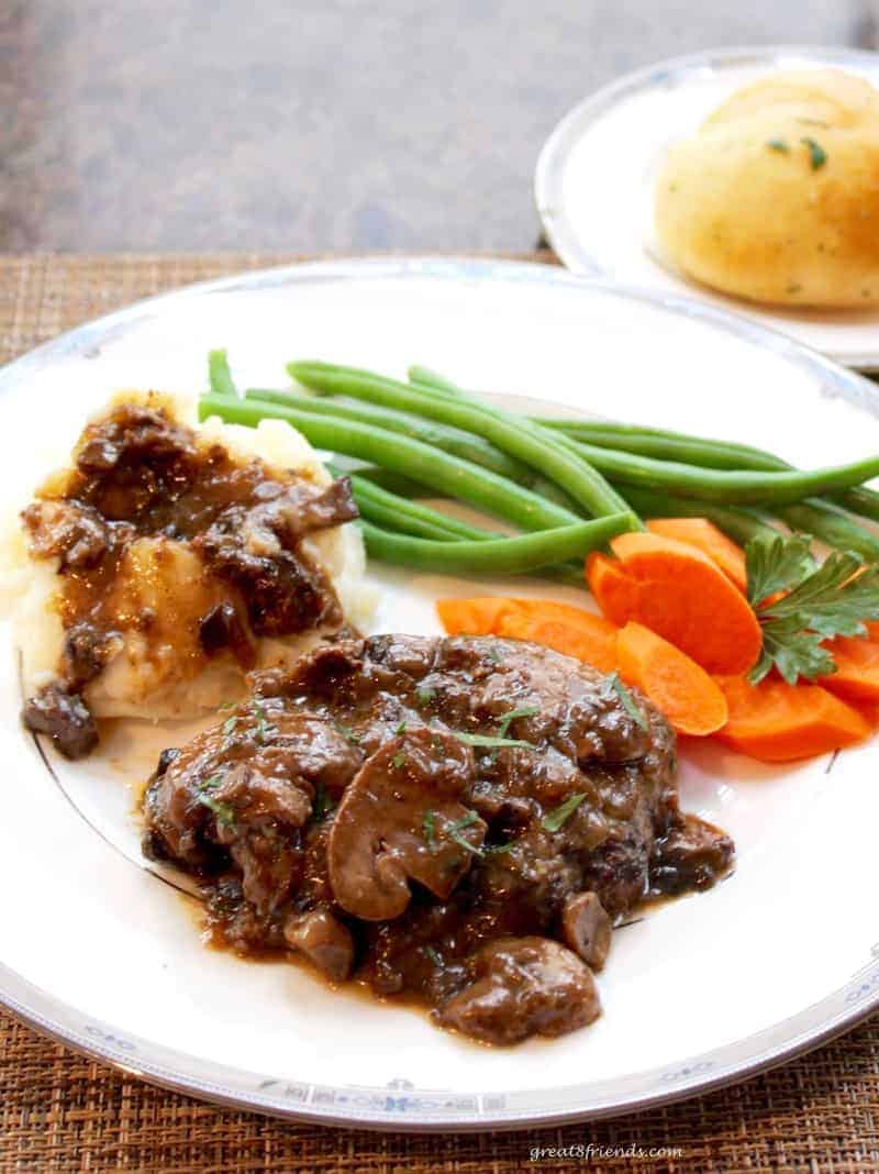 Salisbury Steak with Mushroom Onion Gravy served with carrots and green beans and a roll.