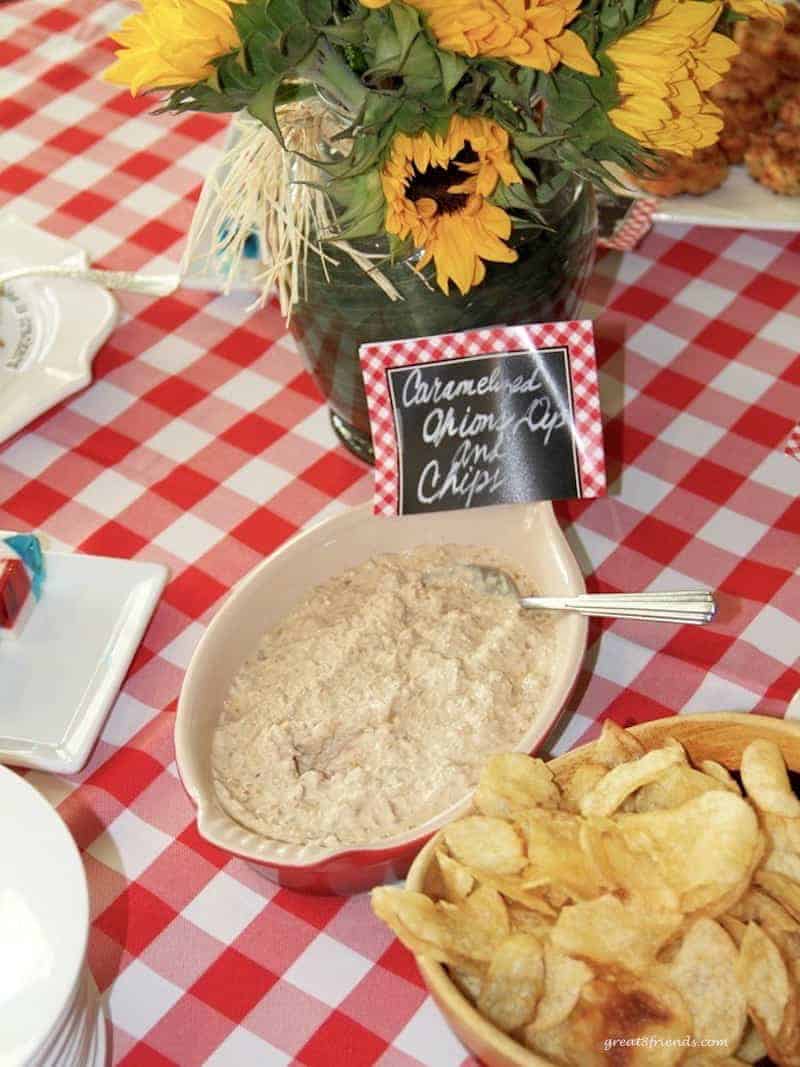 Onion dip and potato chips on red and white checked tablecloth.