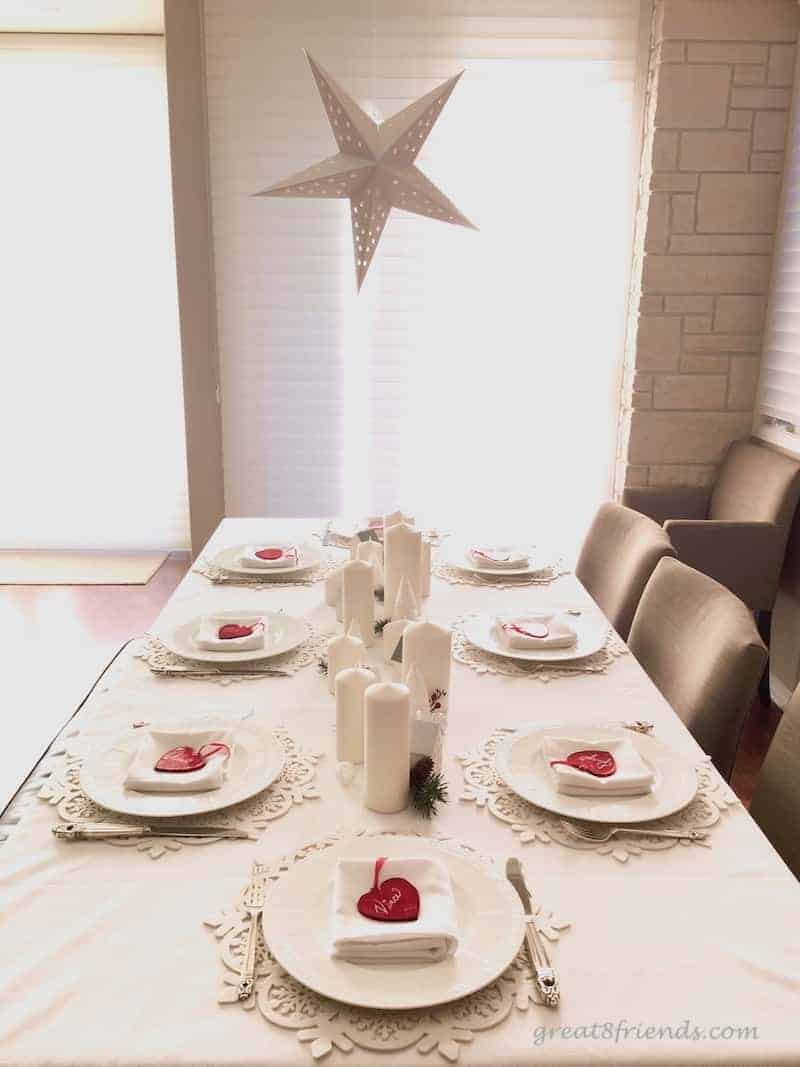 A Christmas white table setting with red glass heart place cards