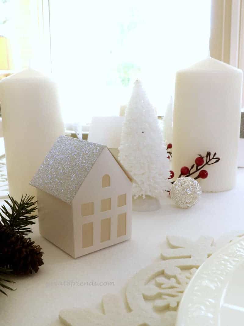 A Danish Christmas Dinner centerpiece all white with small house, fir tree, candles