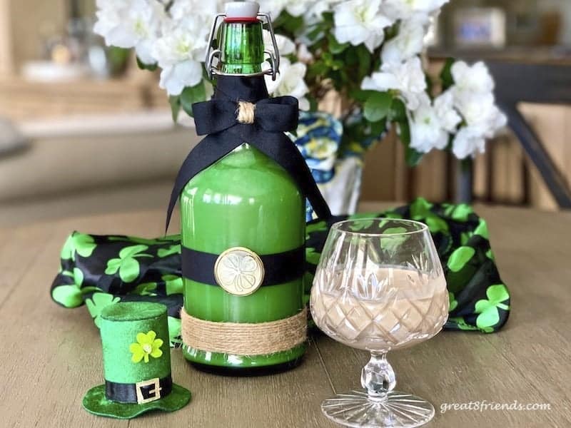 Irish Cream in a green bottle decorated for St. Patrick's Day. With a crystal snifter filled with Irish Cream.