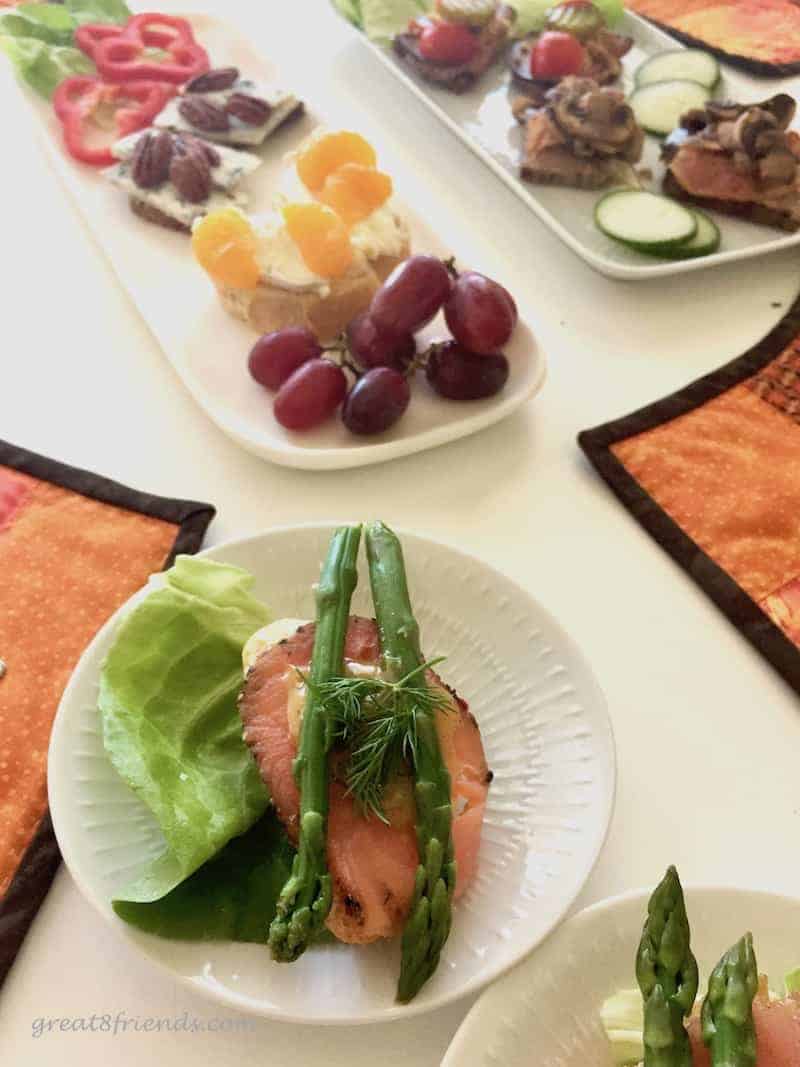 A table set with smorrebrod, with a small plate of a salmon and asparagus sandwich.