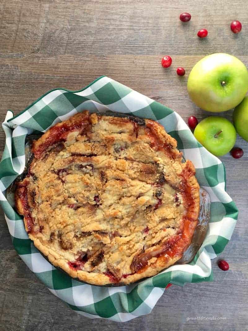 Overhead view of a pie made with apples, cranberries and a buttery crumb topping.