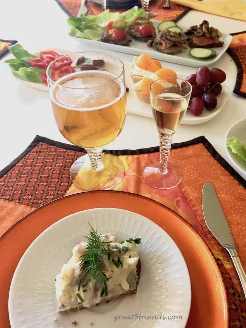 A place setting for smorrebrod with a beer and a glass of aquavit.