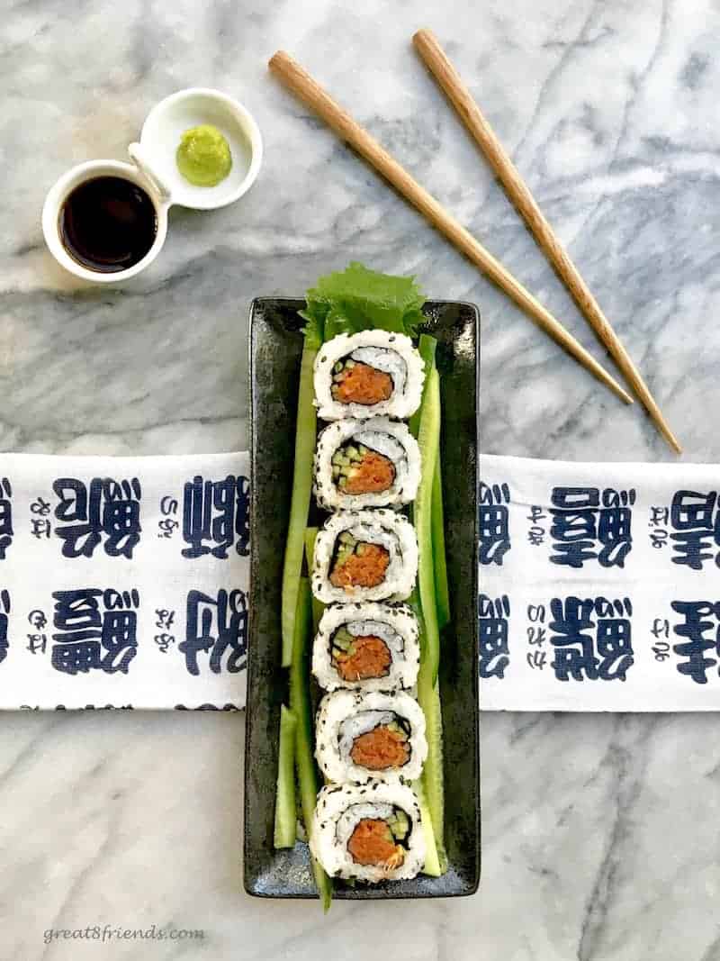 A plate of sushi with chopsticks and sauces.