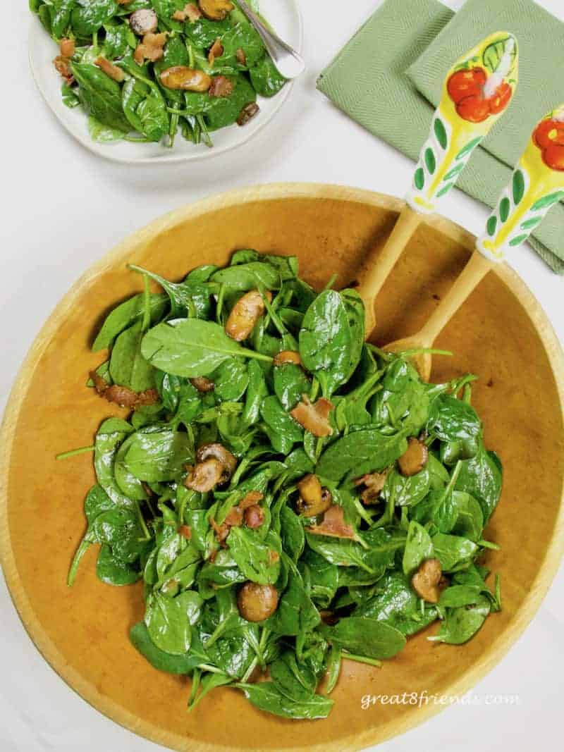 Overhead shot of spinach salad in a wooden bowl.