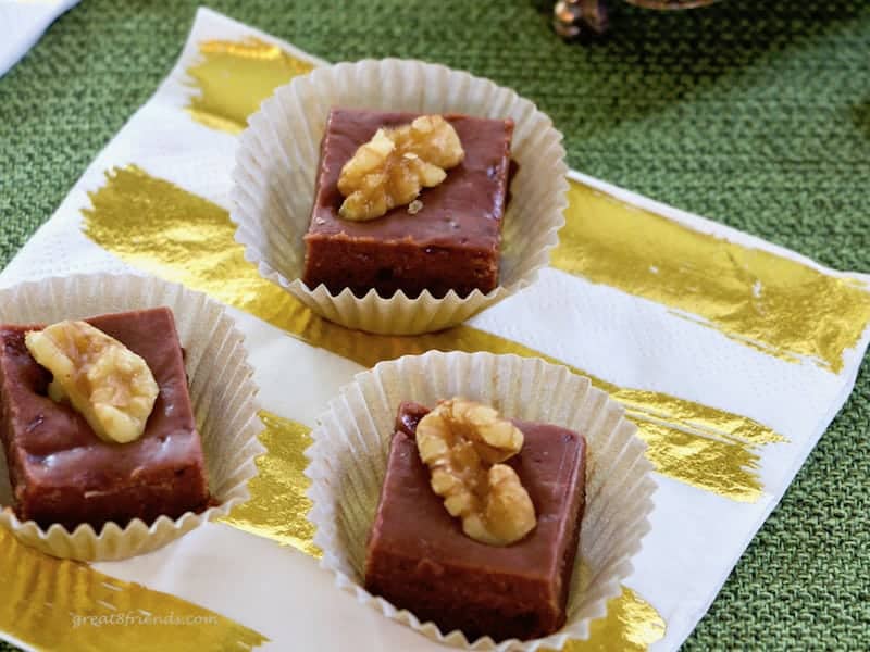 Three pieces of Irish Cream Fudge topped with walnut on a gold and white napkin.