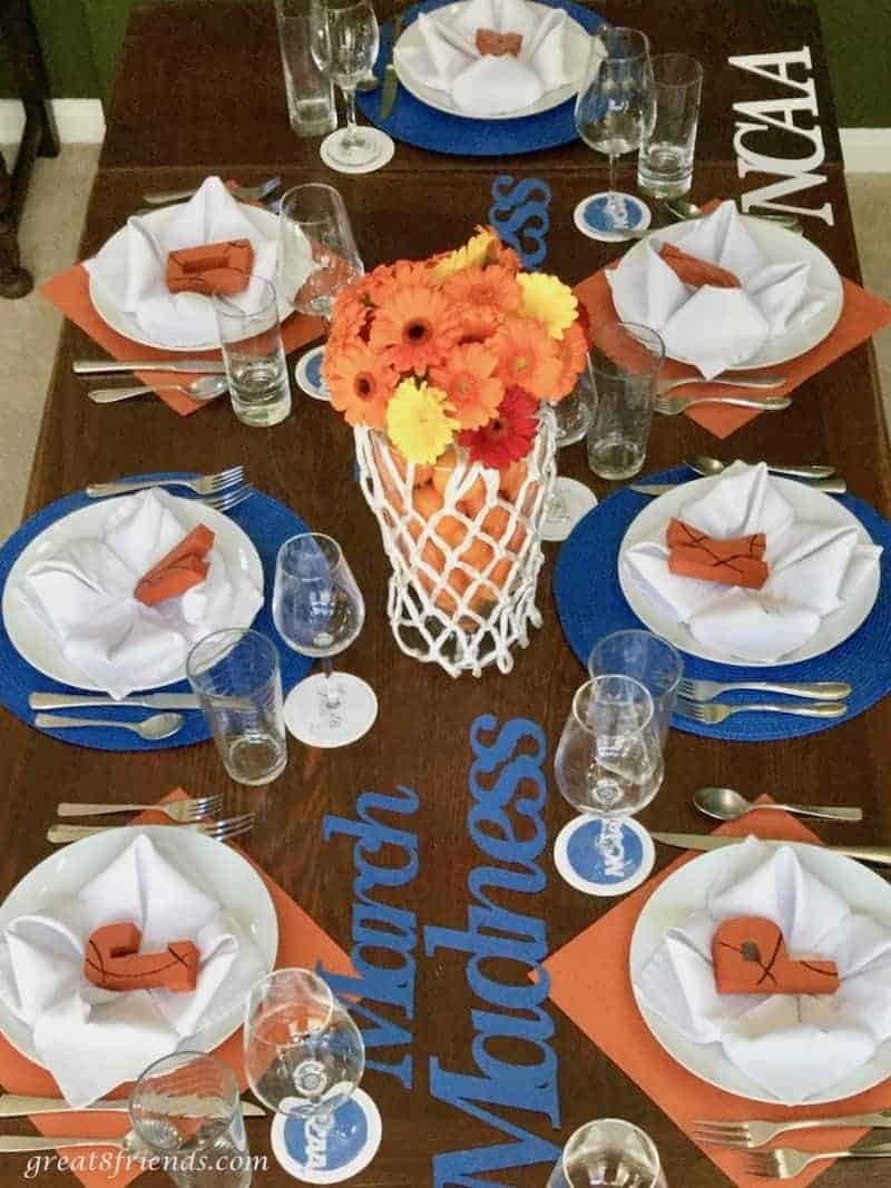 Overhead shot of our March Madness dinner table with a basketball hoop filled with orange and yellow gerbers as the centerpiece.