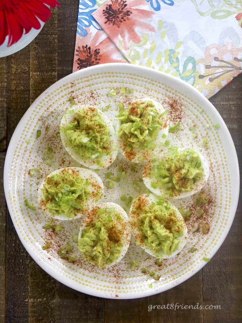 Overhead view of avocado deviled eggs on a white plate.