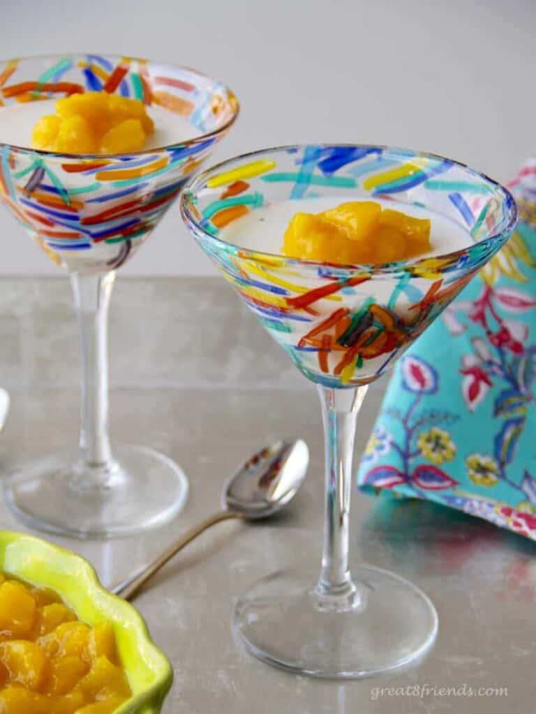 Two martini glasses filled with vanilla panna cotta and topped with mango compote.