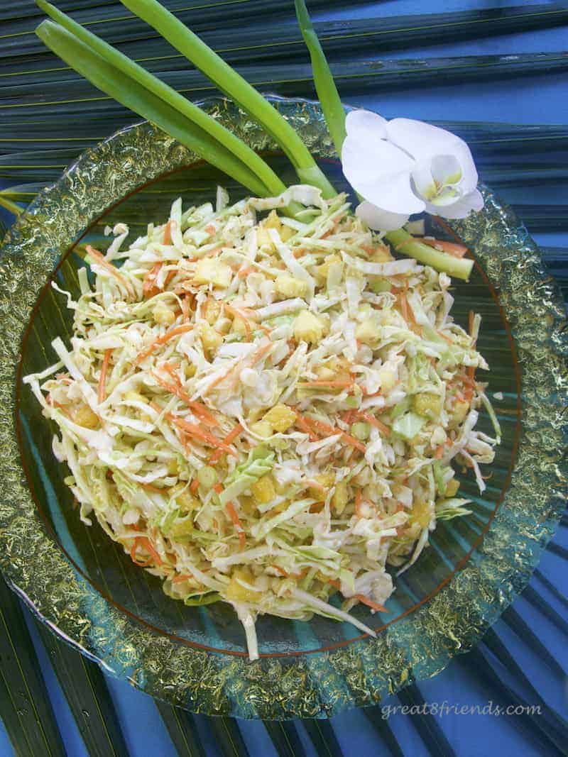 Overhead shot of Pineapple Sesame Slaw in a yellow glass bowl garnished with spring onions and an orchid.