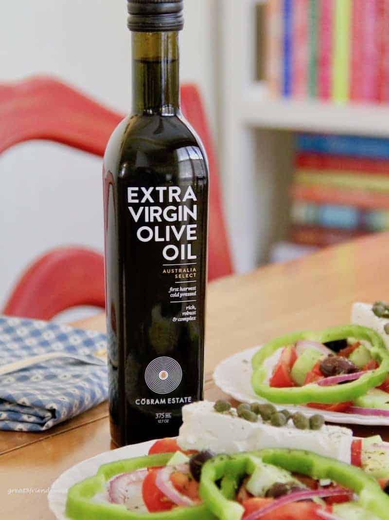 Two plated greek salads and a bottle of Cobram Estate Olive Oil.