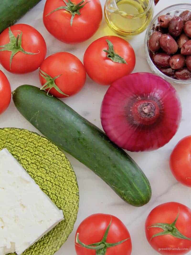 Overhead view of fresh ingredients, tomatoes, cucumber, red onion, fresh feta and kalamata olives.