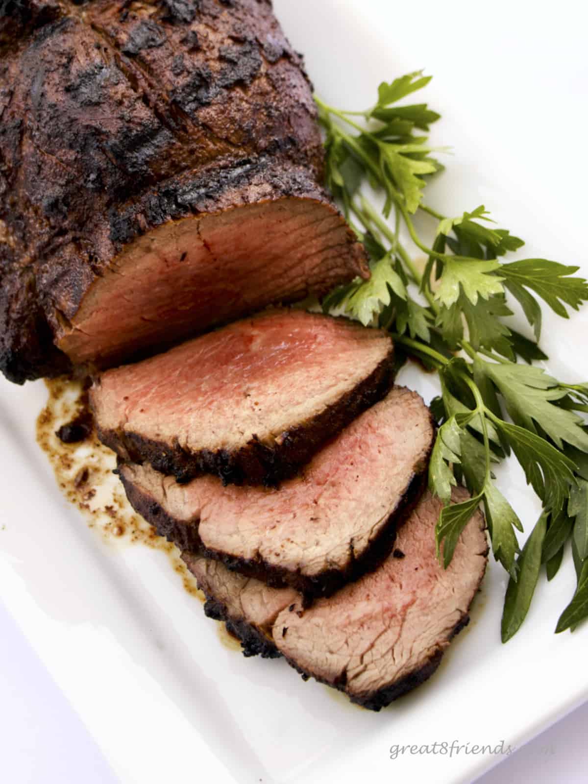 A Grilled Beef Tenderloin with 3 slices fanned out surrounded by parsley.