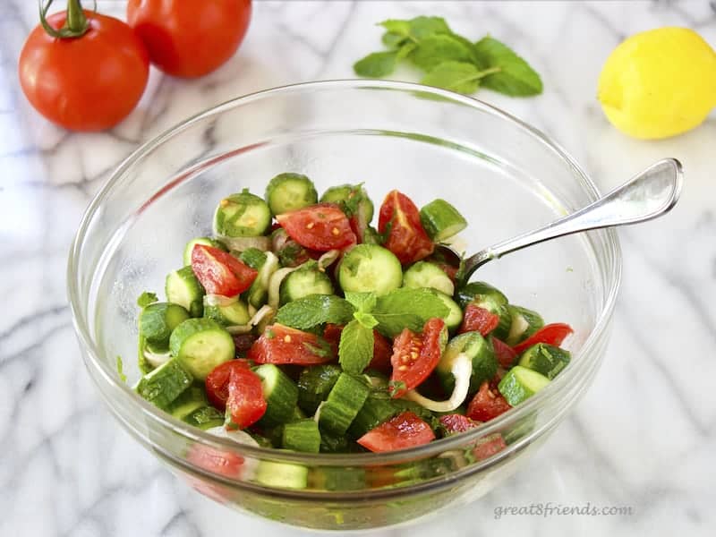 Minted Cucumber Tomato Salad in glass serving bowl with serving spoon.