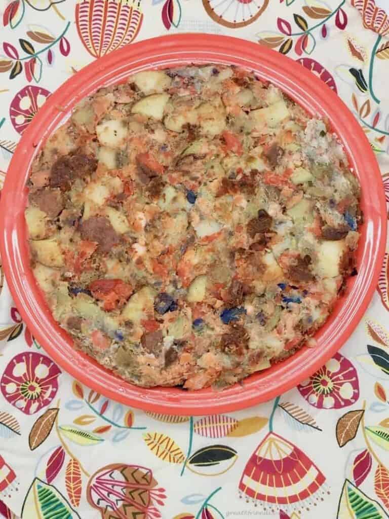 Overhead view of a large plate of salmon hash sitting on a colorful tablecloth.