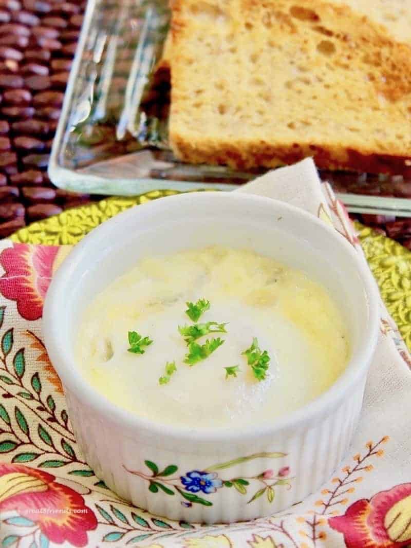 A egg baked in a white porcelain ramekin sitting on a flowered napkin.