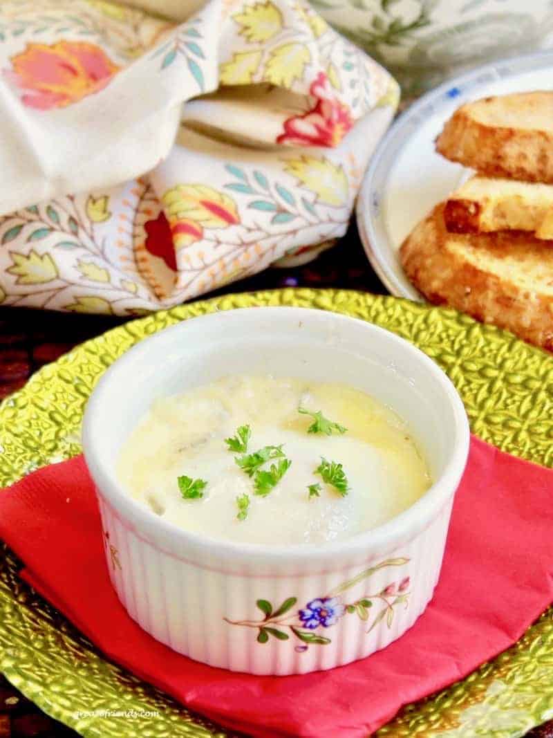 This is baked eggs with mushrooms and parmesan cream in an individual ramekin with parsley sprinkled on top.