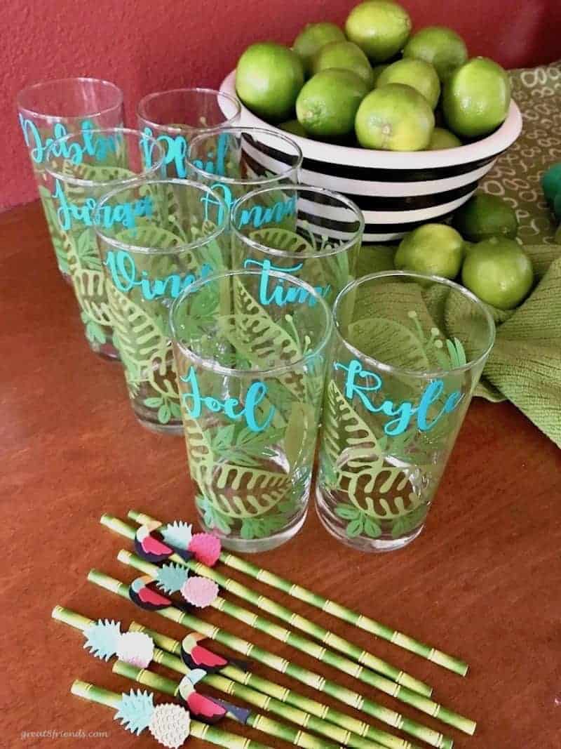 Drinking glasses with names and palm leaves with limes in the background.
