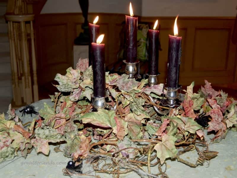 Burgundy candles on a candelabra surrounded by spooky fall leaves.