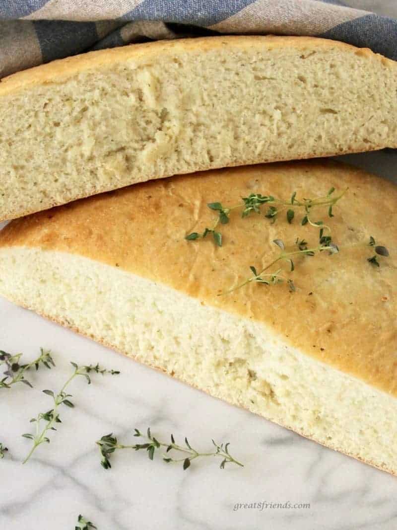 One loaf of Onion Thyme Focaccia Bread cut in half and garnished with fresh thyme.