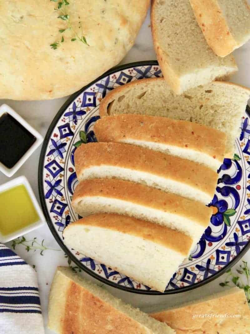 Sliced Savory Onion Thyme Focaccia Bread served on a blue colorful plate with olive oil and balsamic vinegar on the side.