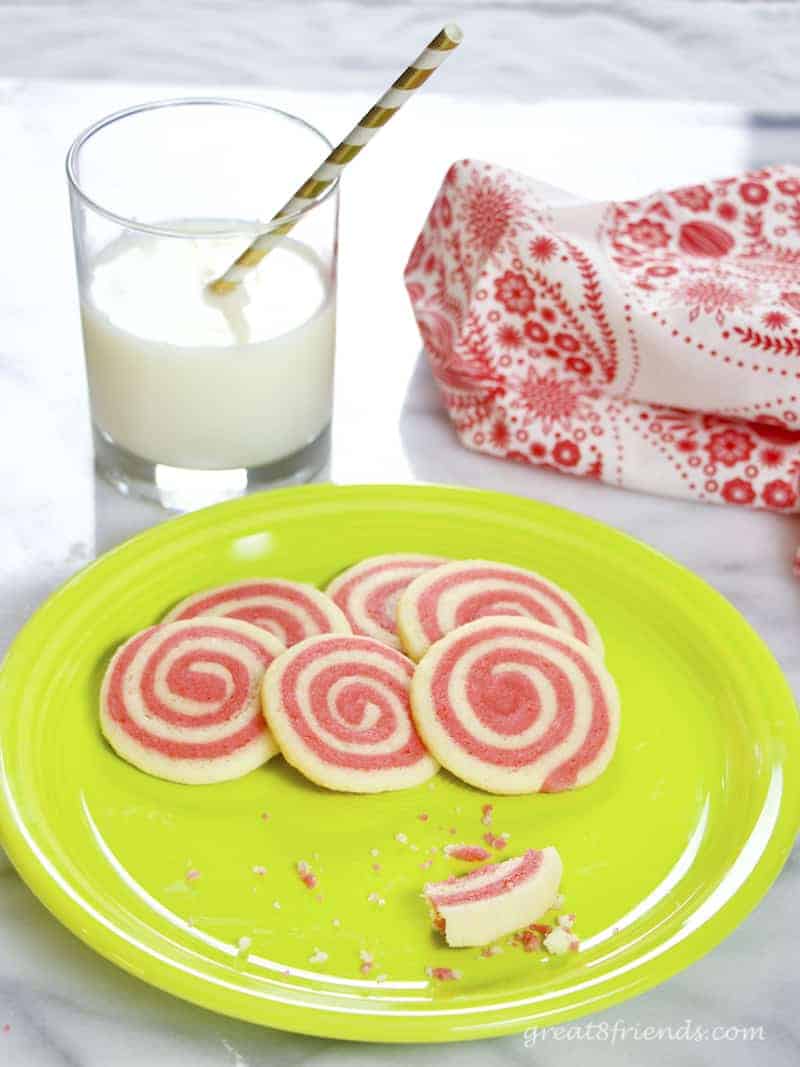 Six Peppermint Pinwheel Cookies on green plate with glass of milk with straw. Cookies and milk!
