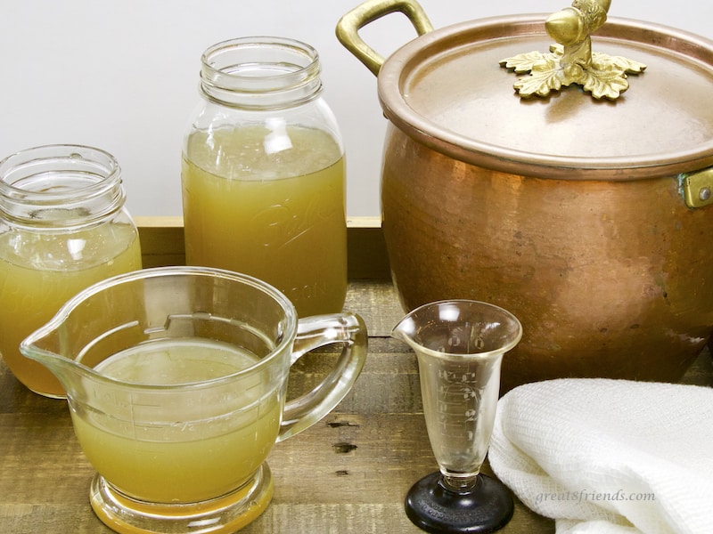 Chicken Stock in jars and measuring cup with copper pot in background