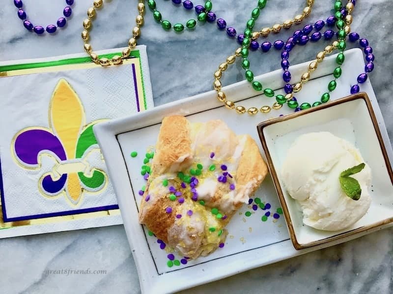 Slice of king cake with scoop of ice cream and some beads.