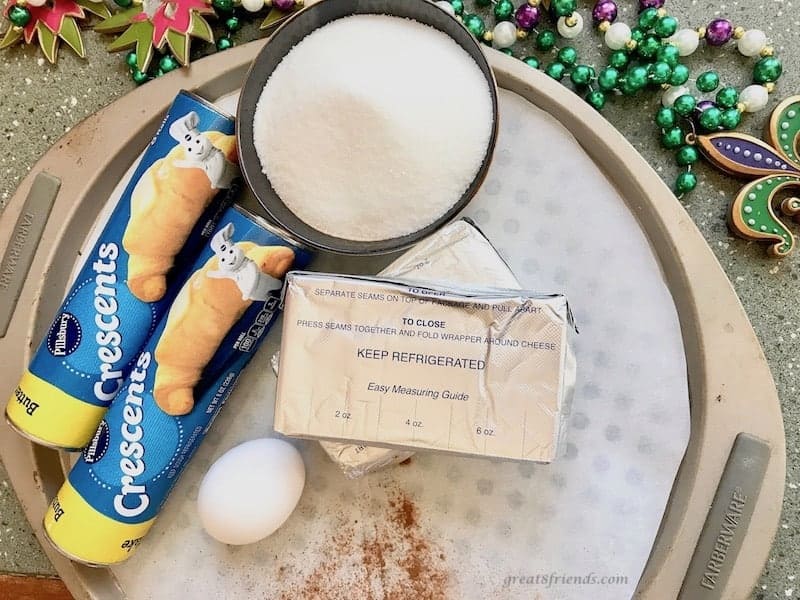 A round tray with two Pillsbury crescent rolltubes, sugar, cream cheese and an egg. 