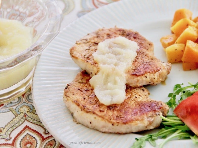 Pork chops served with applesauce on top.