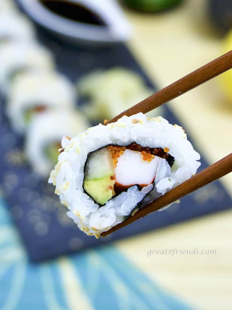 California roll piece held with chopsticks close up