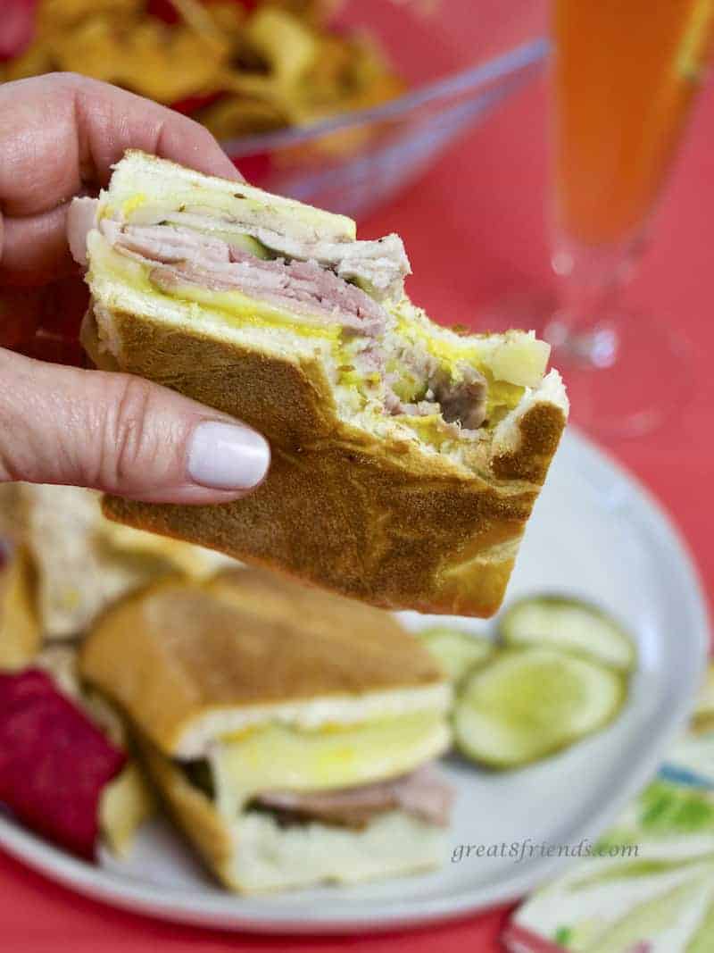 Cubano Sandwich held in hand with bite out of it.