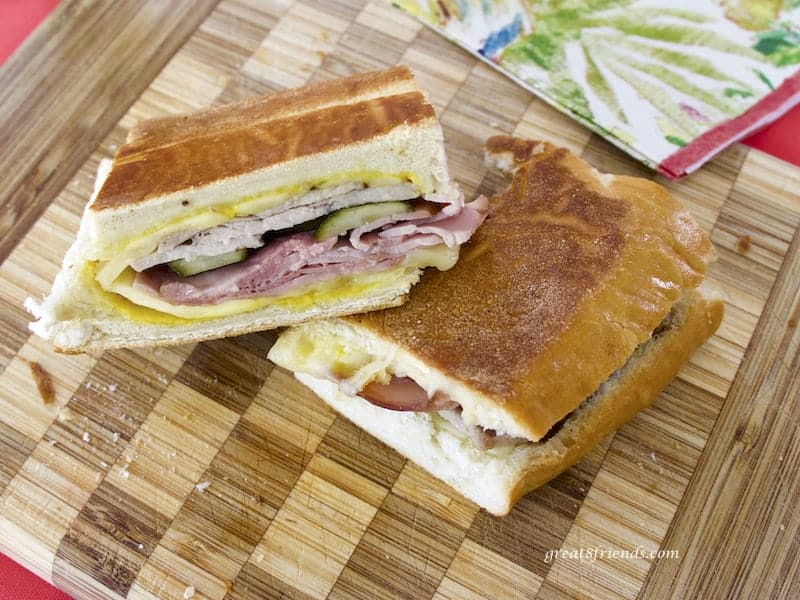 Cuban sandwich cut in half on a checkered wooden board.