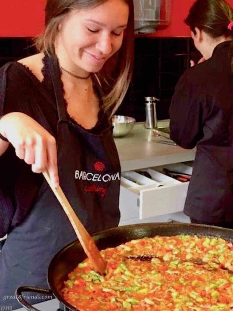 A woman cooking paella on the stove.