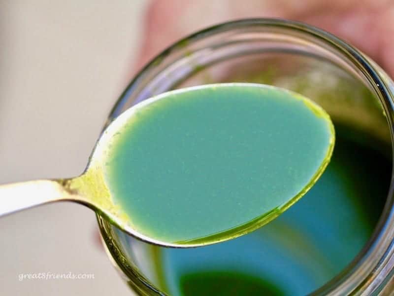 Up close look at bright green arugula oil in a teaspoon.