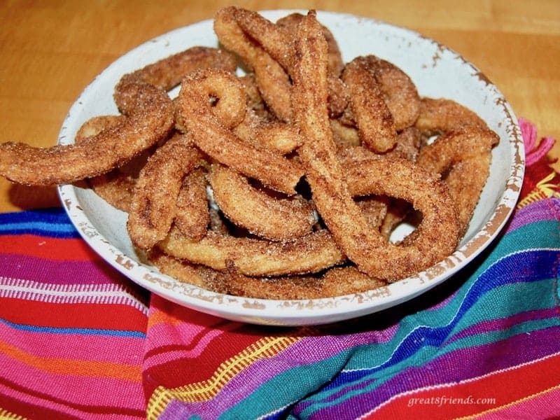 White plate piled with curly churros.